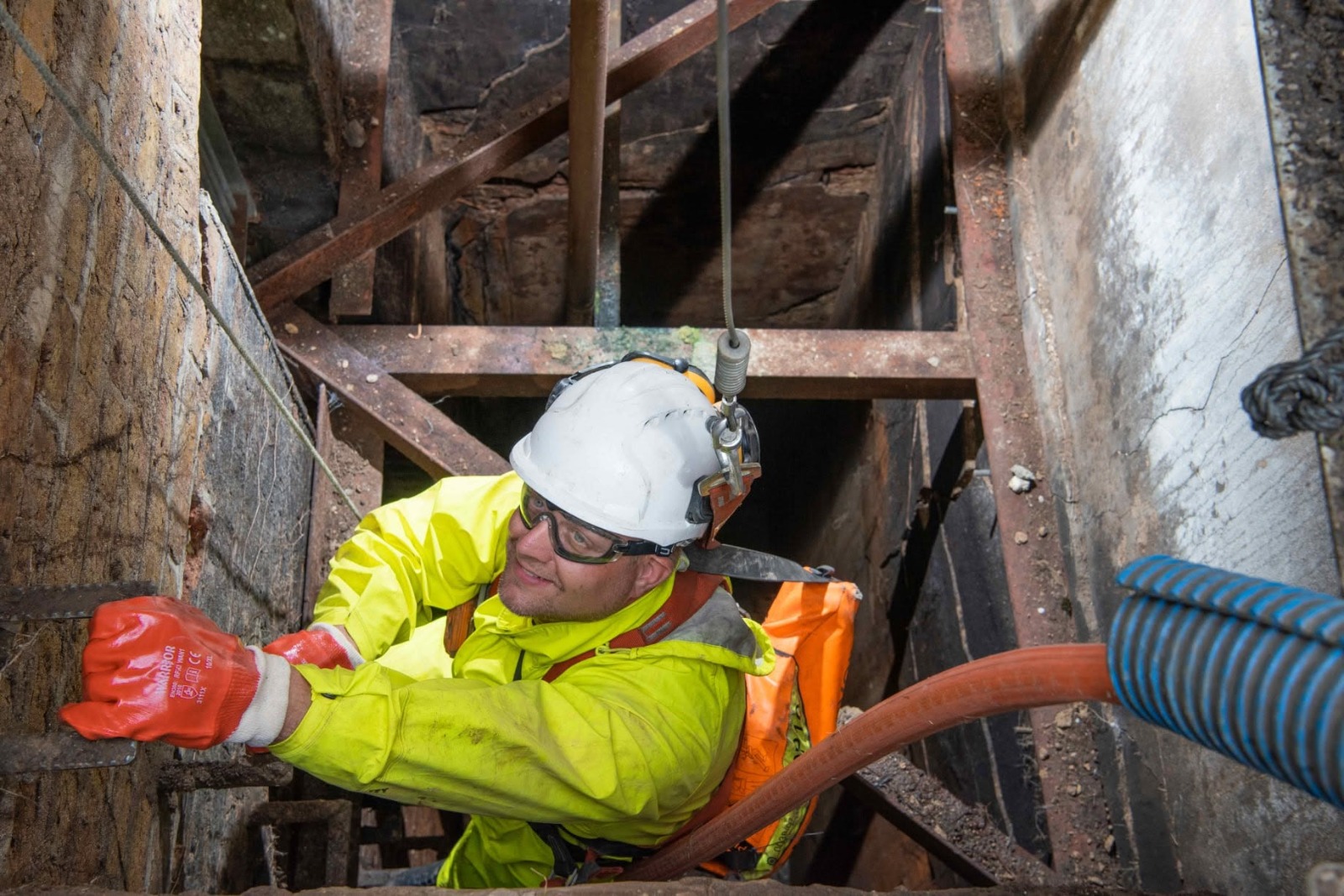 Drainage engineer descending a deep access shaft to carry out structural drain pipe repairs