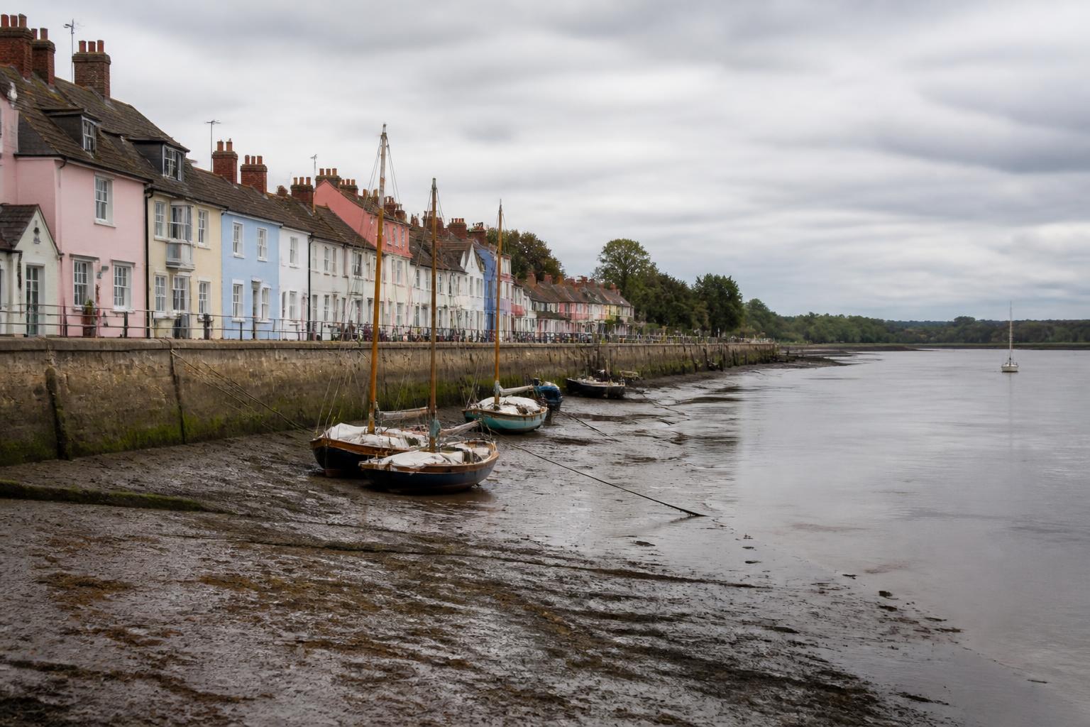 Pastel-painted riverside cottages and sailing boats at low tide on the River Colne, Wivenhoe, Essex