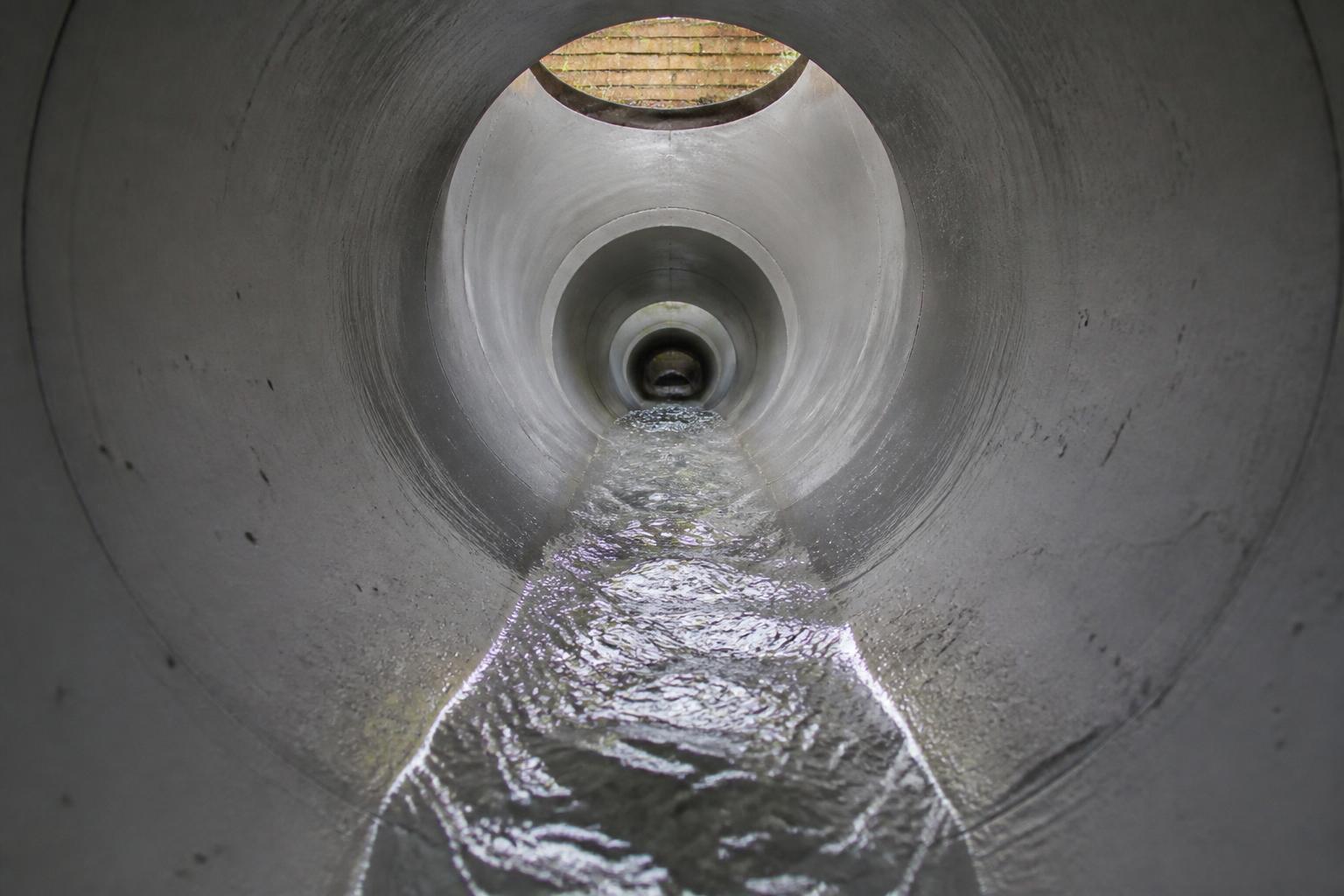 Interior of a freshly cleaned underground drainage pipe with clear water flowing — domestic and commercial drain cleaning across Essex