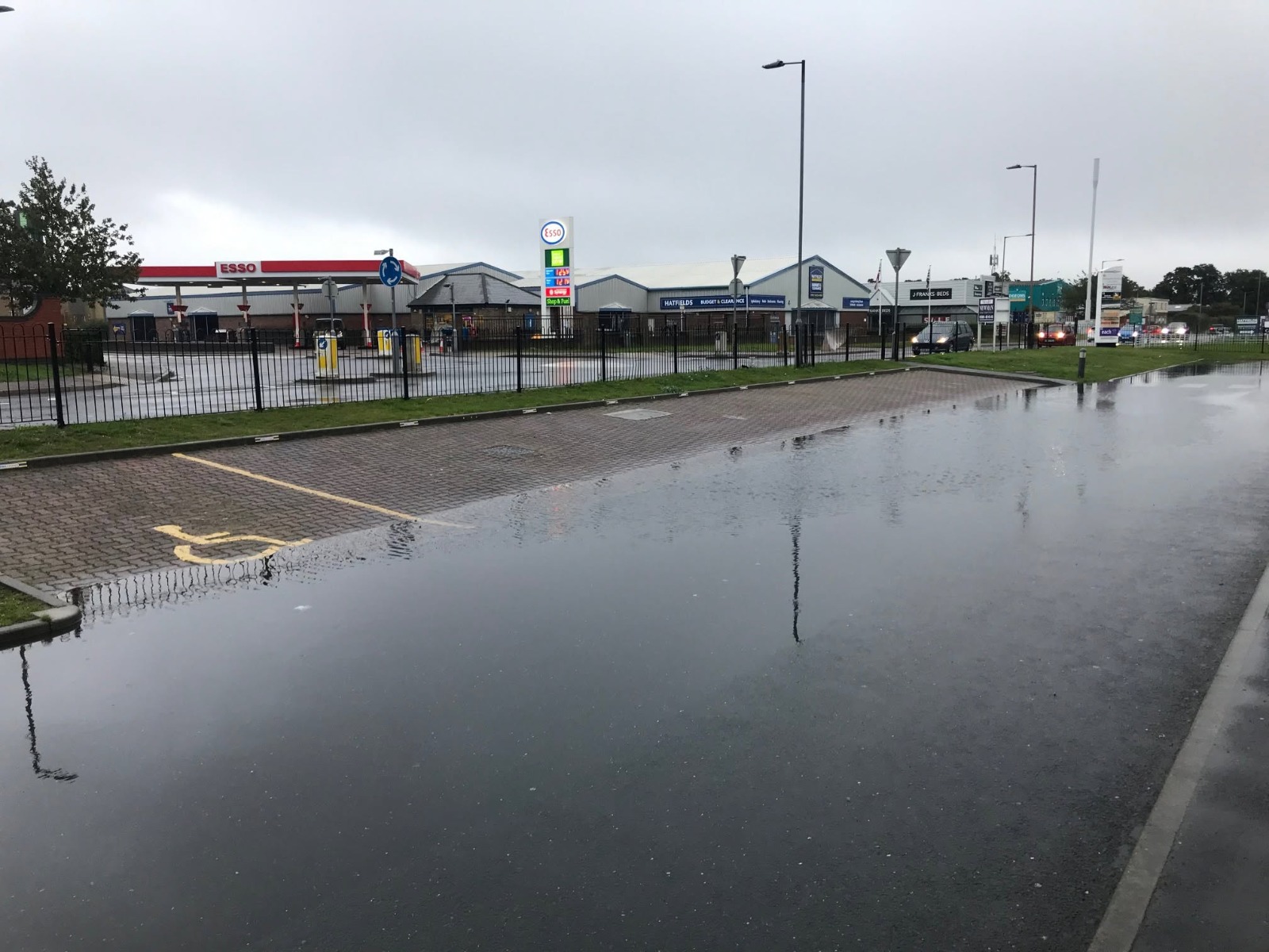 Flooded petrol-station forecourt before high-pressure water jetting cleared the drains